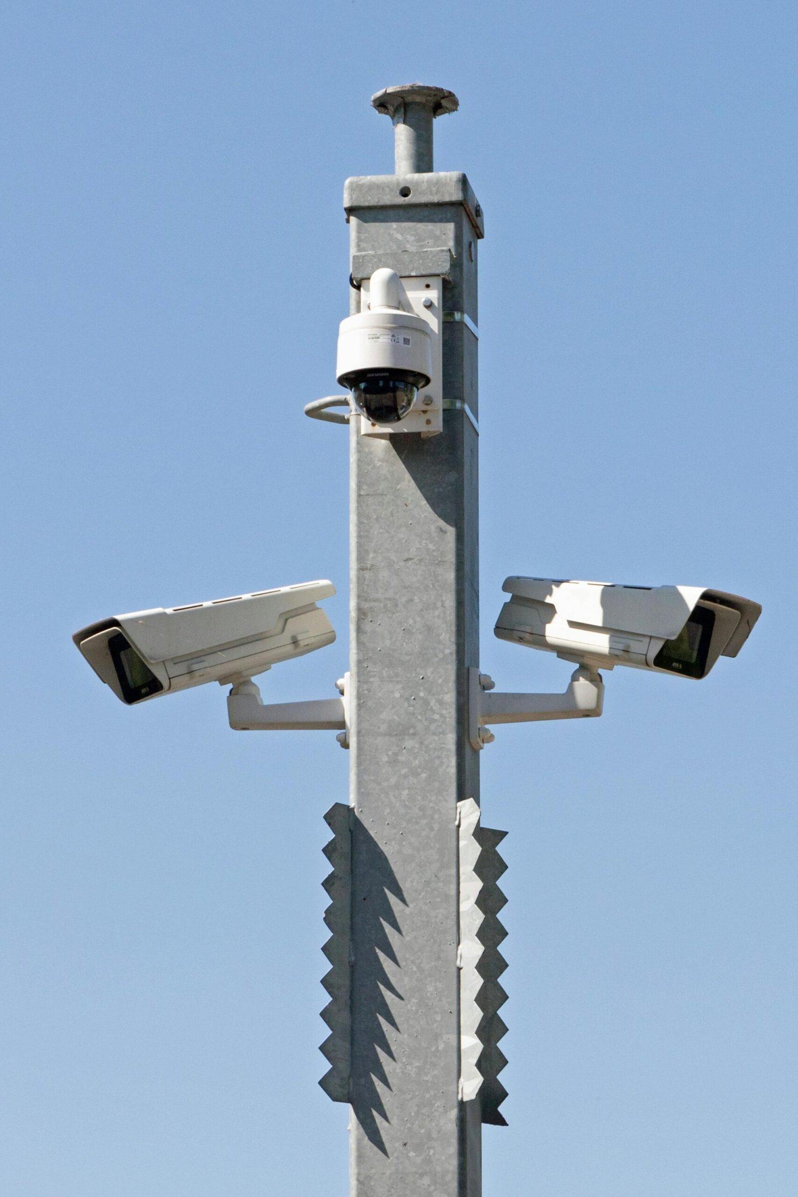 Elite Investigation & Protection for Legal Professionals, Insurance Carriers, and Private Individuals. Outdoor surveillance system with multiple cameras mounted on a metal pole against blue sky.